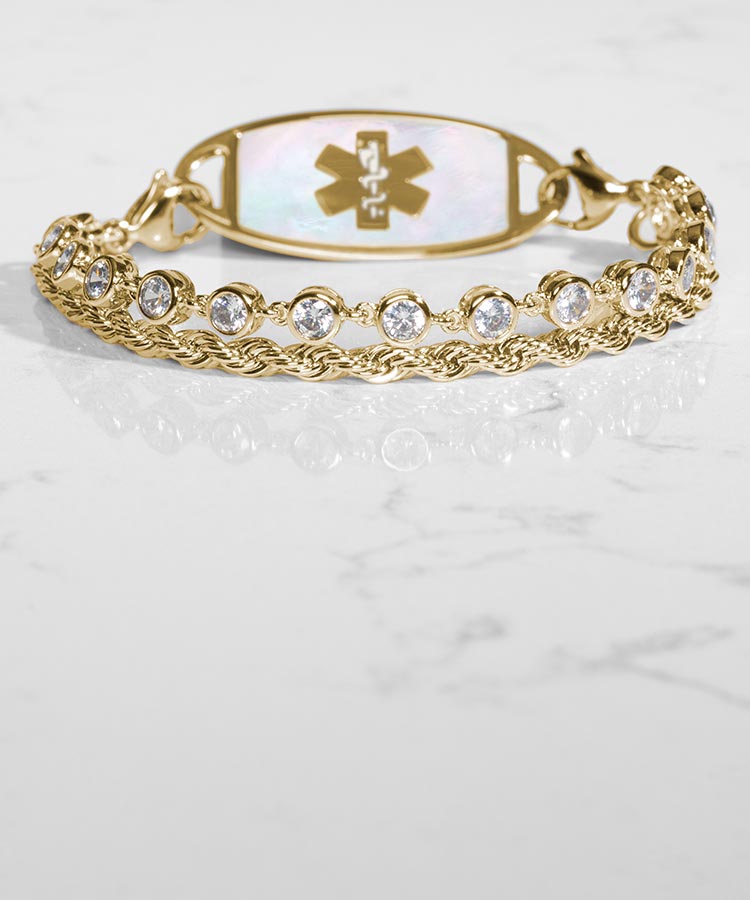 Woman with hand on book wearing silver tennis bracelet with mother of pearl medical ID tag