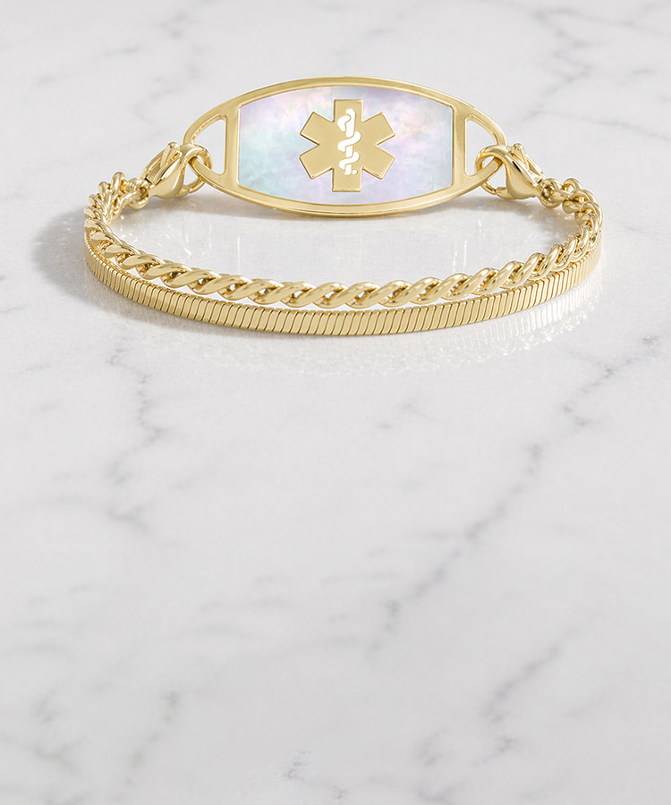 Woman with hand on book wearing silver tennis bracelet with mother of pearl medical ID tag