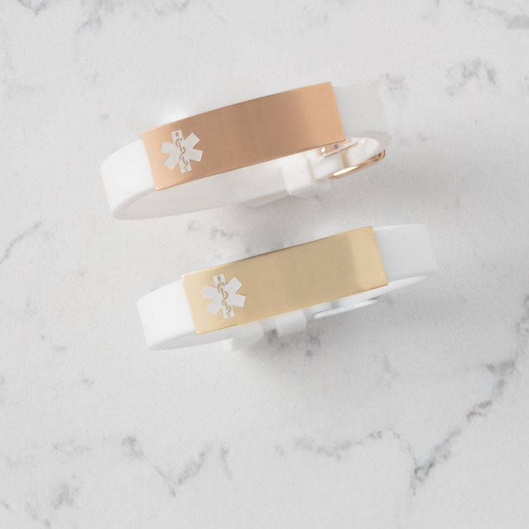 White silicone with rose gold medical ID tag or gold medical ID tag on marble background