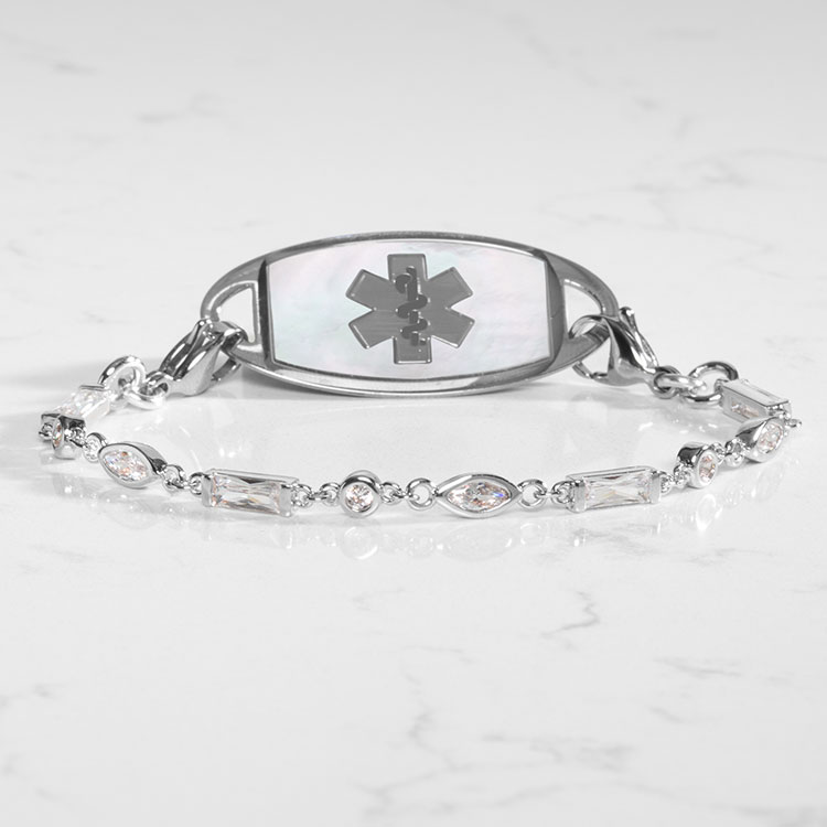 Crystal and silver tennis bracelet with mother of pearl medical ID tag on marble background