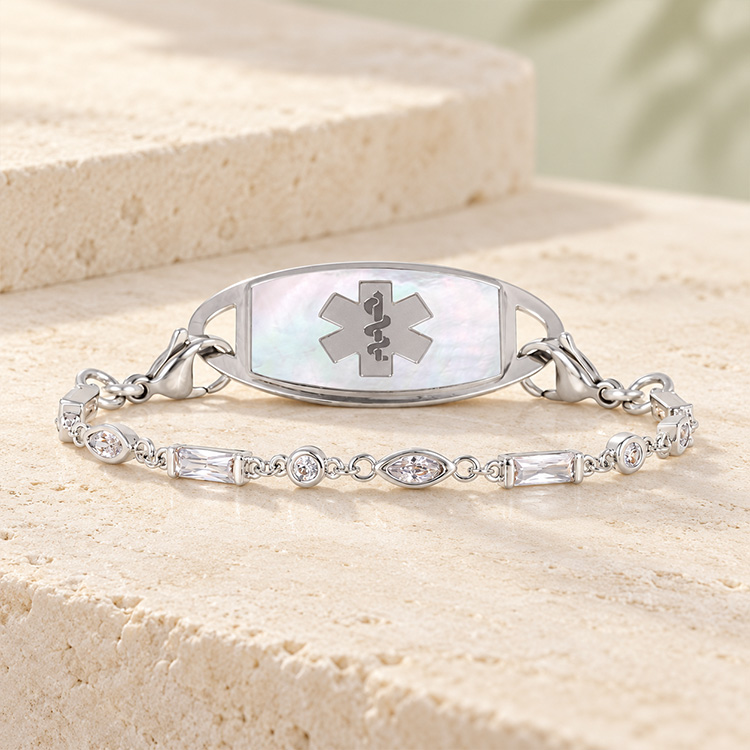 Crystal and silver tennis bracelet with mother of pearl medical ID tag on marble background