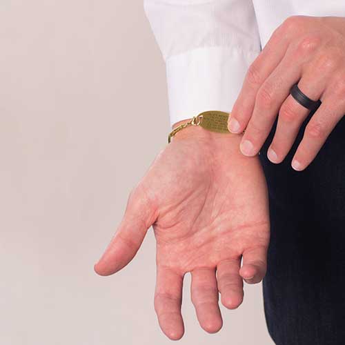 Man showing custom laser engraving on gold medical ID tag