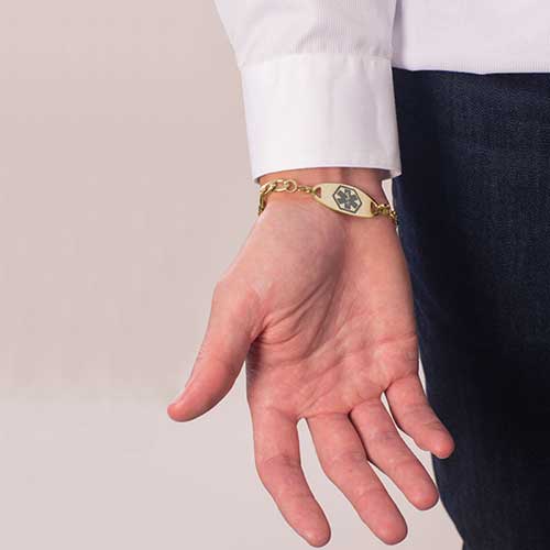 Man with hand upturned showing gold medical alert tag with grey medical symbol