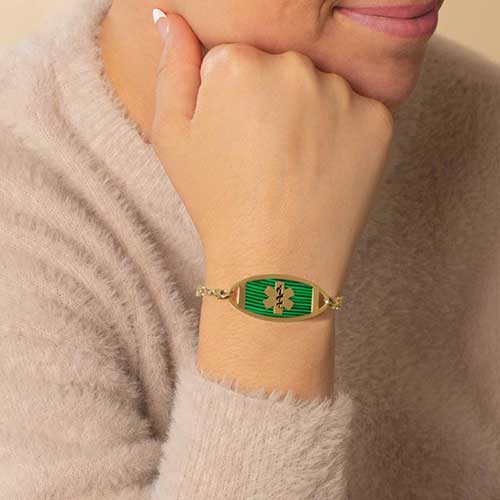 Woman with hand on chin wearing gold and malachite green medical ID tag