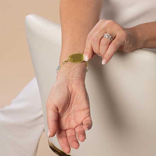 Woman wearing custome laser engraved medical ID tag in gold tone