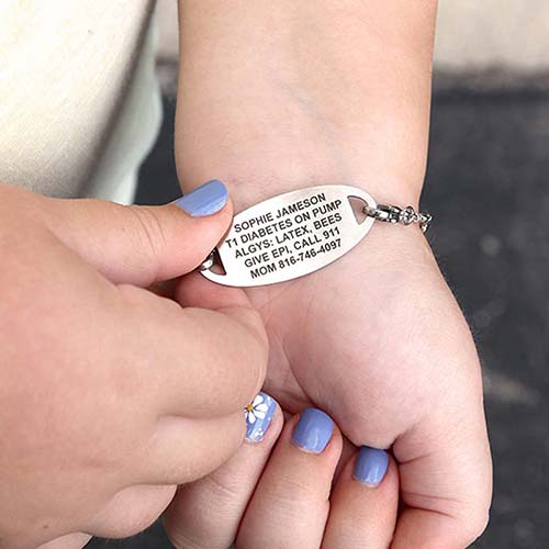 Girl wearing the Sunny Skies Medical ID Bracelet with a medical ID tag turned over to show the custom engraving on the back