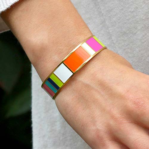 Woman wearing Key West Medical ID Cuff.  Orange pink white magenta lime navy and teal color blocks,yellow gold background