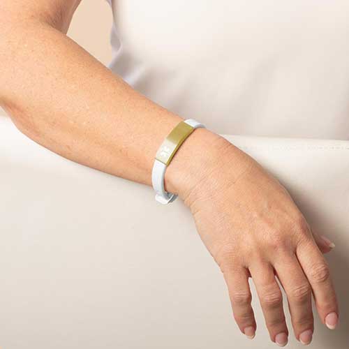 Woman wearing white silicone medical ID alert bracelet with brushed gold medical ID tag