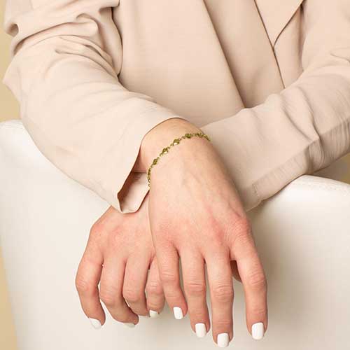 Woman wearing gold chain medical ID bracelet with tiny heart links.