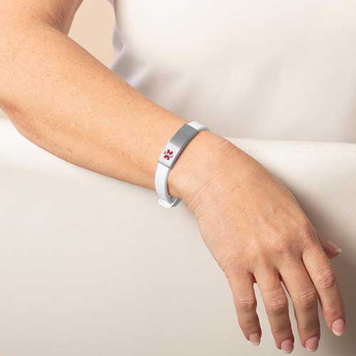Woman wearing silicone bracelet with Silver medical ID and red caduceus.