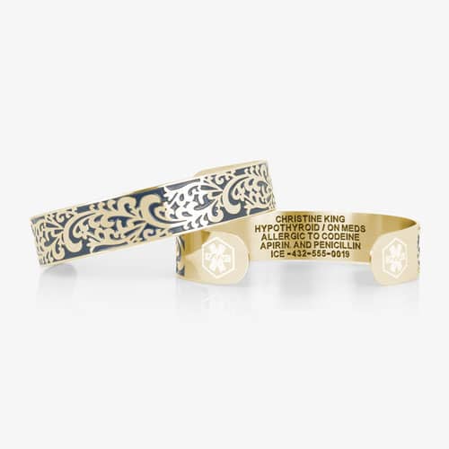 Gold-tone medical ID cuff shown front and back, featuring blue filigree detailing, medical symbols, and custom engraving.
