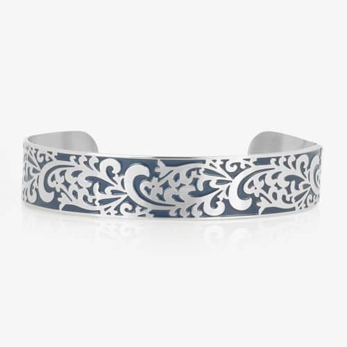 Silver-tone cuff bracelet featuring an intricate filigree pattern with blue inlay across the front.