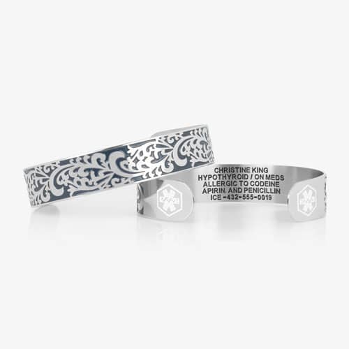Silver-tone medical ID cuff shown front and back, featuring blue filigree detailing, medical symbols, and custom engraving.