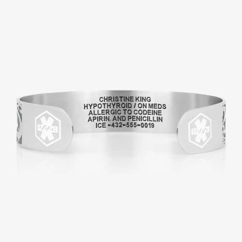 Back of a silver-tone medical ID cuff showing personalized emergency information engraving and medical symbols on each end.