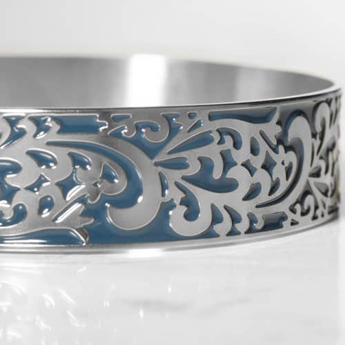 Close-up of a silver-tone cuff bracelet featuring an intricate filigree design with blue inlay.