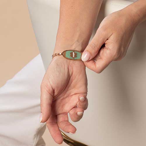 Woman displaying Decorative Medical ID tag with Amazonite inlay and rose tone caduceus. 