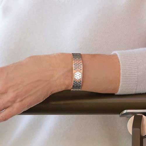 Woman wearing rose gold with blue decorative pattern medical alert cuff bracelet
