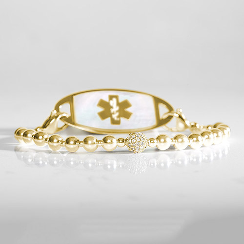 Gold tone beaded stretch medical ID bracelet on marble
