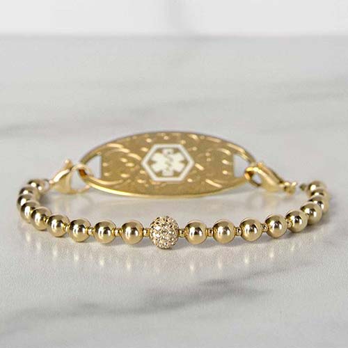 Gold tone beaded stretch medical ID bracelet on marble
