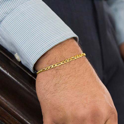 Man with hand on stair rail wearing low profile gold medical alert bracelet chain