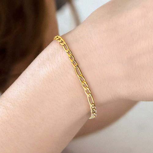 Woman holding glass and wearing delicate gold medical alert chain bracelet