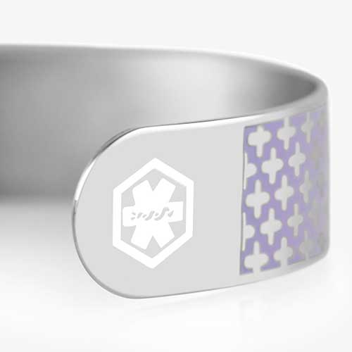 A close up view of silver tone medical ID cuff bracelet with lavender pattern and white medical symbol at the end of the cuff.