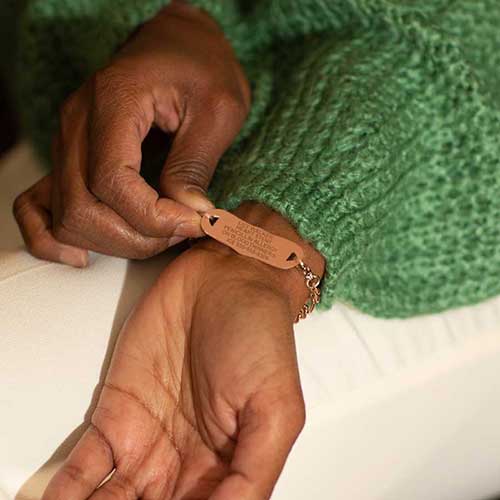 Woman showing custom laser engraved rose gold medical ID Tag