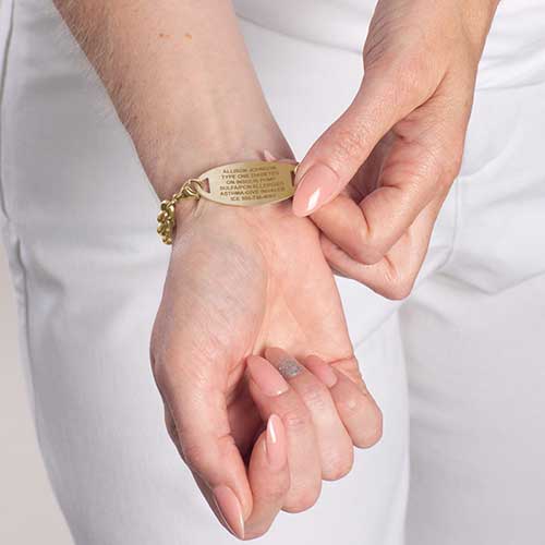 Woman showing precision laser engraving on gold tone stainless steel medical ID tag.