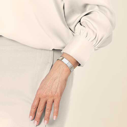 Brown and tan color block medical ID cuff bracelet on woman with hand in pocket