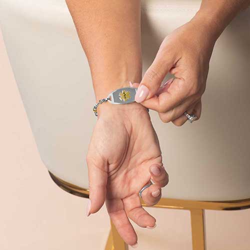 Woman displaying her Medical ID Tag with gold tone medical symbol