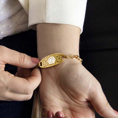 Woman showing decorative gold tone medical alert tag with white medical caduceus symbol