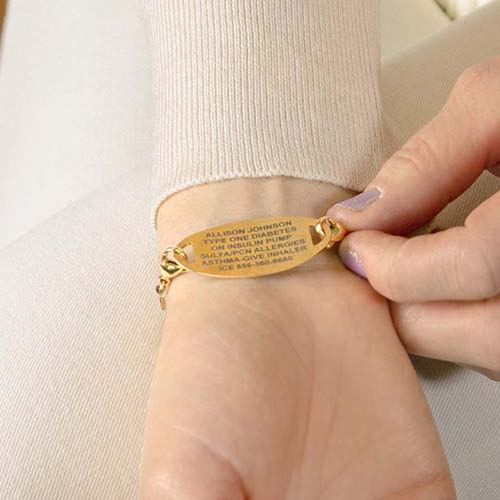 Woman showing custom laser engraving gold medical alert tag