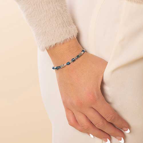 Woman with hand in pocket wearing blue and silver beaded stretch medical ID bracelet.