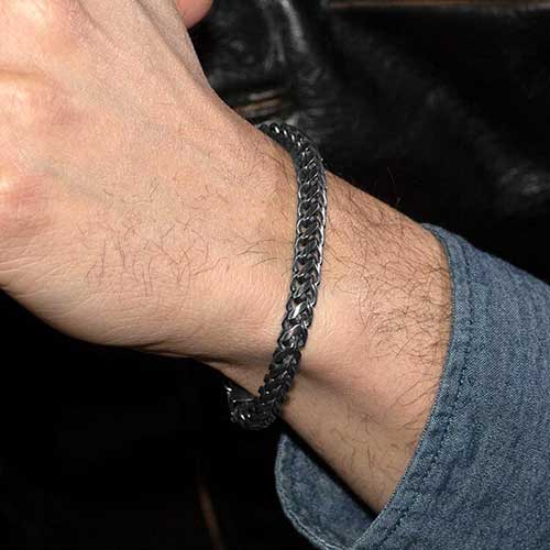 Man in denim shirt wearing antiqued woven stainless steel chain medical alert bracelet.