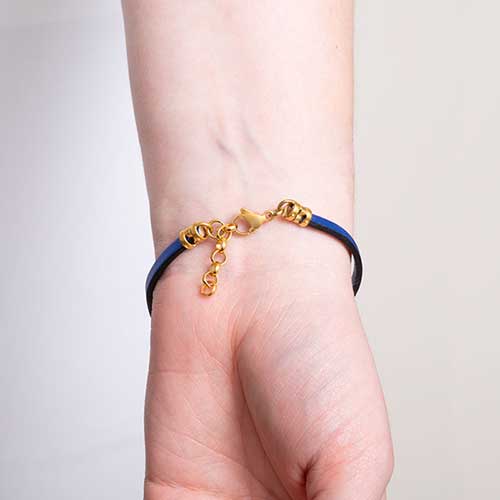 Navy blue metallic leather bracelet on arm showing the gold tone adjustable chain and lobster clasp that sits opposite the med ID tag.