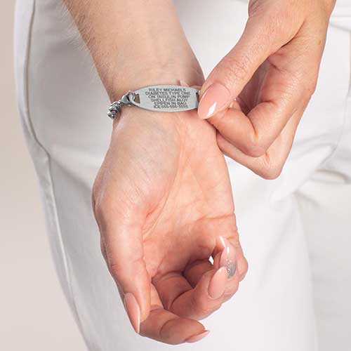 Woman showing premium laser engraving on stainless steel medical ID tag.