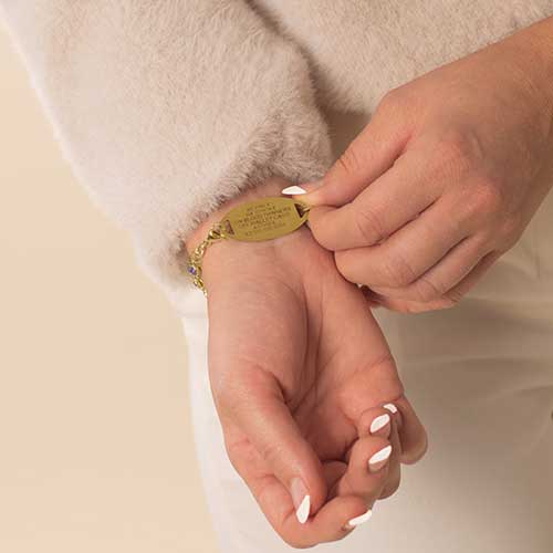 Woman showing premium laser engraving on gold tone stainless steel medical alert tag.