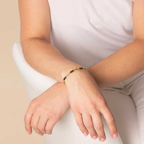 Woman wearing 12k gold plated and hematite beaded stretch medical alert bracelet.