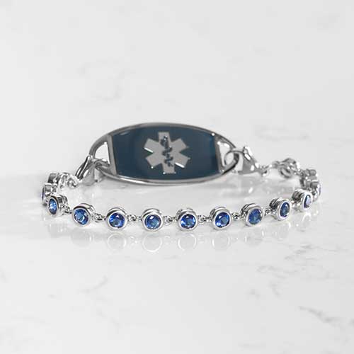 Rhodium and palladium plated women's medical alert bracelet with sapphire tone, round, bezel set cubic zirconia crystals paired with a stainless steel sapphire traveler medical ID tag.