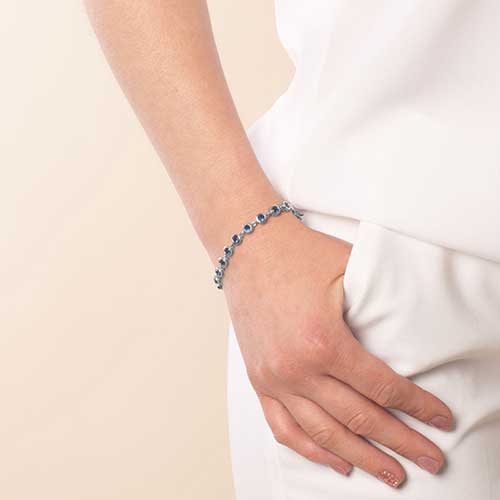 Woman wearing rhodium and palladium plated women's medical alert bracelet with sapphire tone, round, bezel set cubic zirconia crystals.
