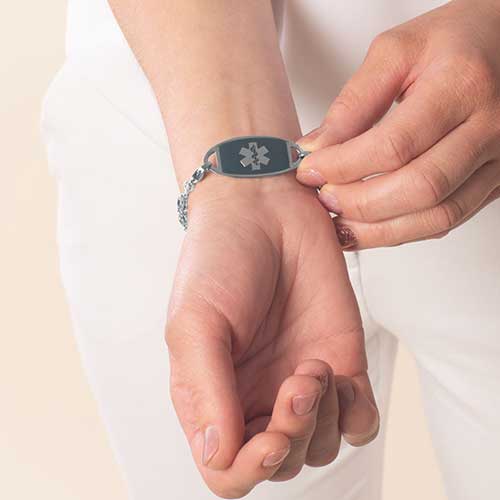 Woman wearing stainless steel medical ID tag with sapphire tone inlay and silver tone medical ID symbol.