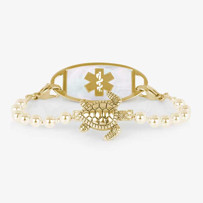 Gold tone beaded bracelet featuring a sea turtle centerpiece, attached to a gold tone medical ID with mother of pearl inlay.