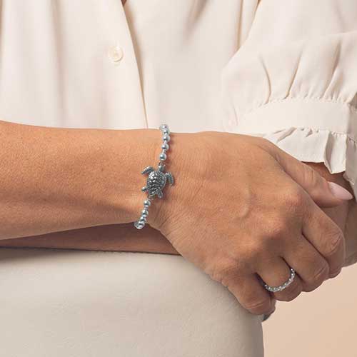 Model wearing beaded bracelet featuring a sea turtle centerpiece