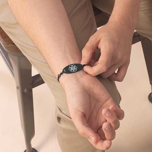 Man displaying black sandblasted medical ID with grey caduceus.