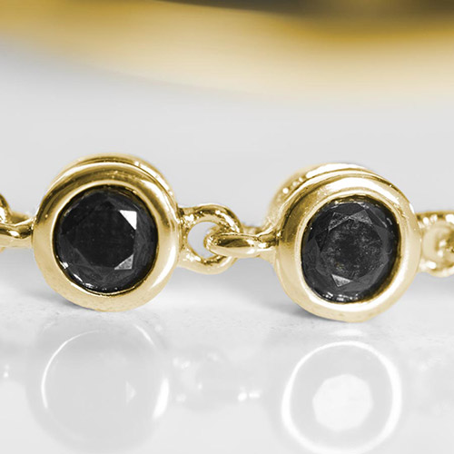 Close-up of black crystal bracelet links in gold settings, showcasing elegant detailing on a stylish medical ID bracelet design.