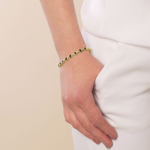 Woman wearing a delicate gold bracelet with black crystal accents, styled as an elegant medical ID accessory for everyday safety.