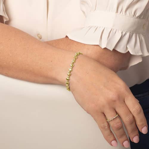 Woman wearing gold heart bead stretch medical alert bracelet with elegant minimalist jewelry styling and feminine everyday fashion look