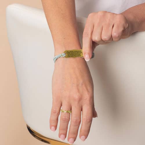 Woman wearing the Avery SmartSize Medical ID Bracelet with a suede light blue tone leather band with the engraving flipped over