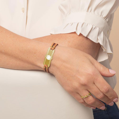 Woman wearing Avery SmartSize Medical ID Bracelet with suede copper tone leather band and adjustable chain with a gold Medical ID with the white medical symbol