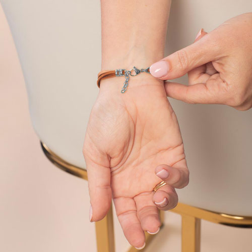 Woman wearing the Avery SmartSize Medical ID Bracelet with a suede copper tone leather band featuring the Silver tone adjustable clasp